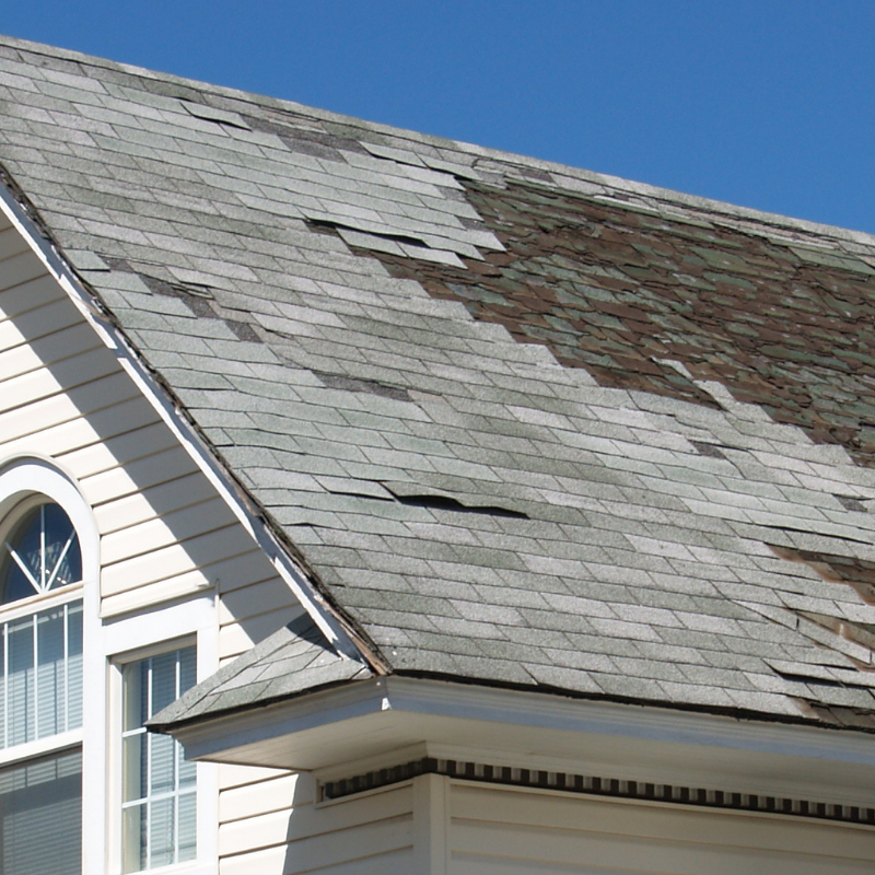 Damaged and missing asphalt shingles on a home needing prompt Navarre roof repair after storm season.