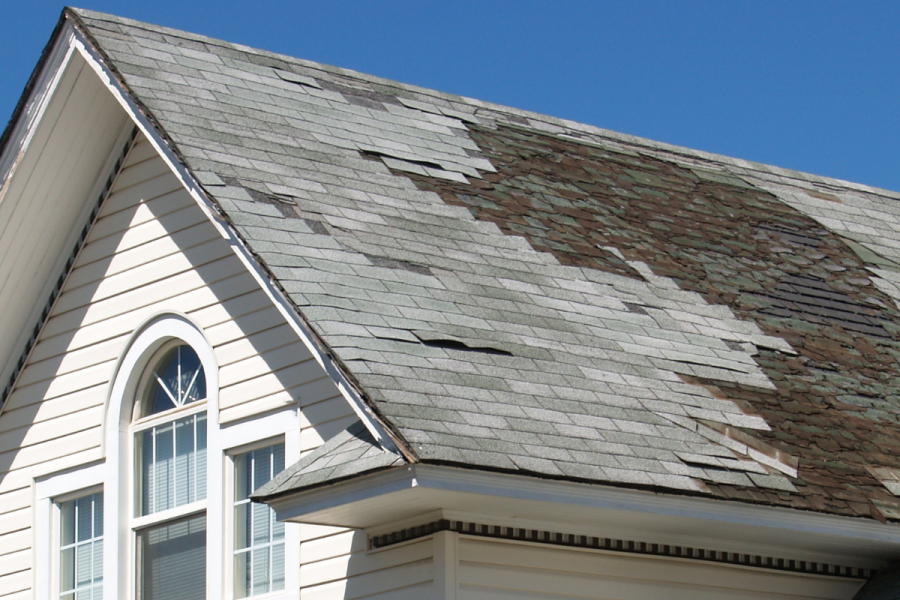Damaged and missing asphalt shingles on a home needing prompt Navarre roof repair after storm season.