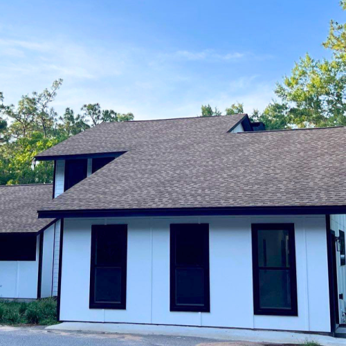 Roof Financing 4 Modern white residential home with black trim and asphalt shingle roof replacement in Milton Florida.