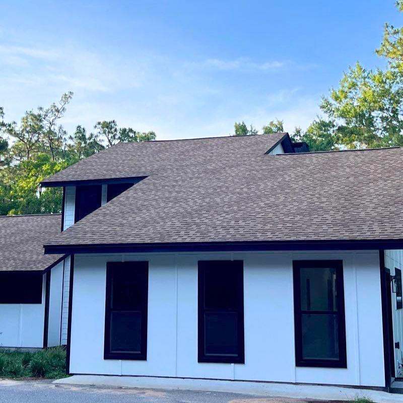 Modern white residential home with black trim and asphalt shingle roof replacement in Milton Florida.