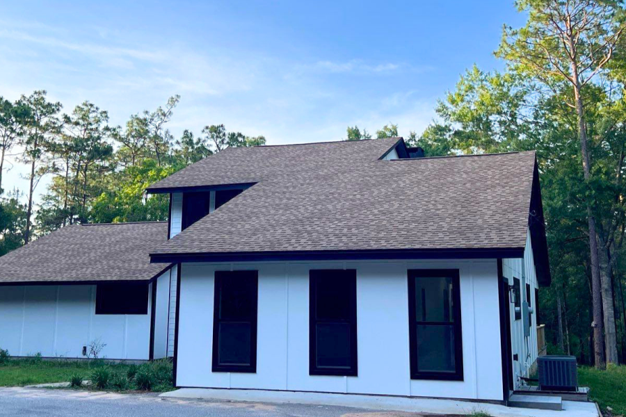 Modern white residential home with black trim and asphalt shingle roof replacement in Milton Florida.